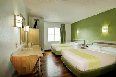 a hotel room with two beds and a desk at Super 8 by Wyndham Aurora East in Aurora