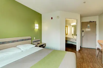 a bedroom with a bed and a bathroom with a sink at Super 8 by Wyndham Aurora East in Aurora