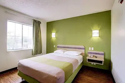 a bedroom with a large bed with a green wall at Super 8 by Wyndham Aurora East in Aurora