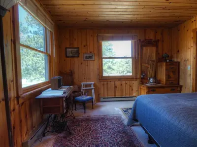 a bedroom with a bed and a desk and windows at MacCracken Homestead in Estes Park