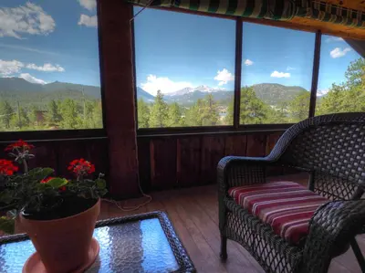 a screened in porch with a couch and a table with flowers at MacCracken Homestead in Estes Park