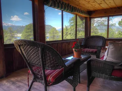 a screened in porch with chairs and a table at MacCracken Homestead in Estes Park