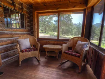 two chairs and a table in a room with windows at MacCracken Homestead in Estes Park