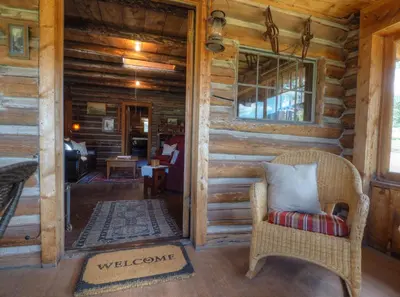 a room in a log cabin with a chair and a mirror at MacCracken Homestead in Estes Park