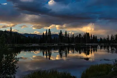 a view of a lake with trees and a cloudy sky at MacCracken Homestead in Estes Park