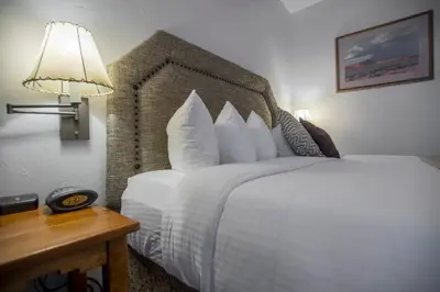 a bedroom with a large bed with a lamp and a table at Table Mountain Inn in Golden