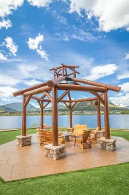a wooden pergola with chairs and tables on a lawn at The Estes Park Resort in Estes Park