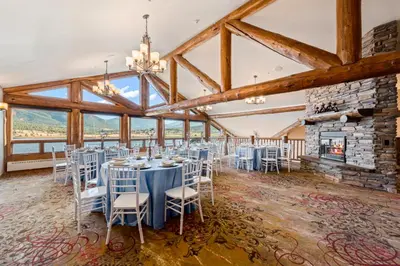 a room with tables and chairs and a fireplace at The Estes Park Resort in Estes Park