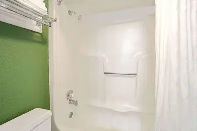 a bathroom with a white shower curtain and a toilet at Super 8 by Wyndham Denver Stapleton in Denver