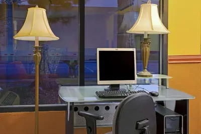 a desk with a computer and two lamps on it at Super 8 by Wyndham Denver Stapleton in Denver