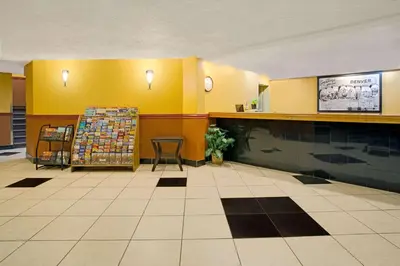 a lobby with yellow walls and a table and a counter at Super 8 by Wyndham Denver Stapleton in Denver