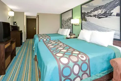 a hotel room with two beds and a flat screen tv at Super 8 by Wyndham Denver Stapleton in Denver