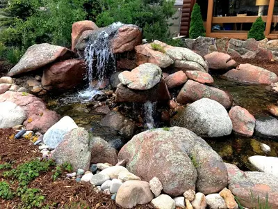 a pond with rocks and a waterfall in a yard at Hotel Estes in Estes Park