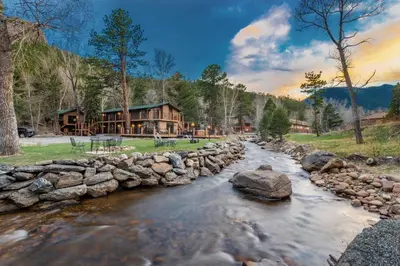 a river in front of a log cabin at 4 Seasons Inn on Fall River in Estes Park