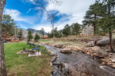 a stream with a picnic table next to a river at 4 Seasons Inn on Fall River in Estes Park