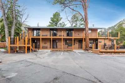 a large house with a tree in a parking lot at 4 Seasons Inn on Fall River in Estes Park