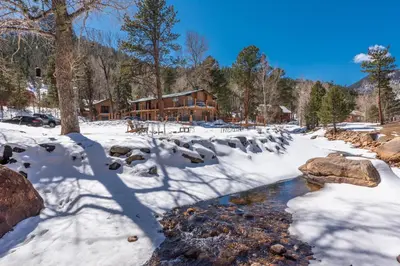 a snow covered yard with a log cabin at 4 Seasons Inn on Fall River in Estes Park