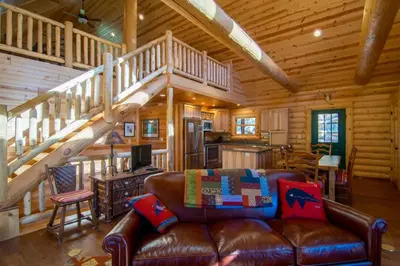 a living room with a leather couch and a staircase at Armstrong Home in Estes Park