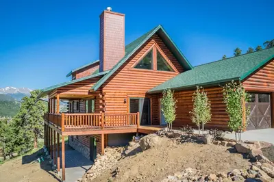 a log cabin with a deck and a house at Armstrong Home in Estes Park