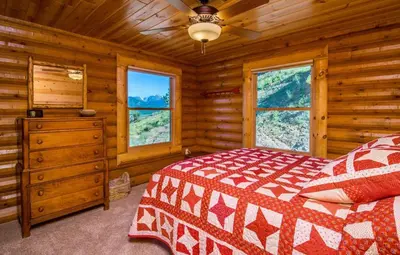 a bedroom with a bed and windows in a log cabin at Armstrong Home in Estes Park