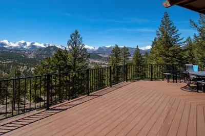 a deck with a table and chairs and mountains at Macmillan Home in Estes Park
