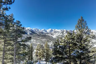 a view of a snow covered mountain range with trees at Macmillan Home in Estes Park