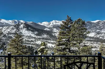 a view of a snow covered mountain range with trees at Macmillan Home in Estes Park
