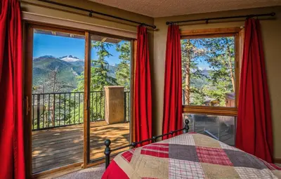 a bedroom with a bed and a balcony with red curtains at Cedar Lower Condominium 2 Bedroom condo in Estes Park