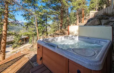 a hot tub on a deck with trees in the background at Cedar Lower Condominium 2 Bedroom condo in Estes Park