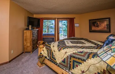 a bedroom with a bed and a television and a window at Cedar Lower Condominium 2 Bedroom condo in Estes Park