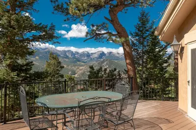 a table and chairs on a deck with a view of mountains at Cedar Upper Condominium 3 Bedroom condo in Estes Park