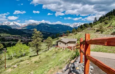 a wooden fence on a hill with mountains in the background at Stevenson Home in Estes Park