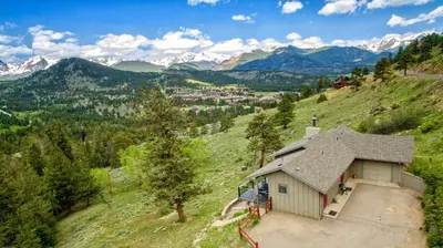a house on a hill with mountains in the background at Stevenson Home in Estes Park