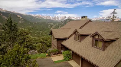 a house with a roof with mountains in the background at Alleman North Condominium 3 Bedroom condo in Estes Park
