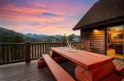 a wooden bench on a deck with a view of mountains at Awestruck Home in Estes Park