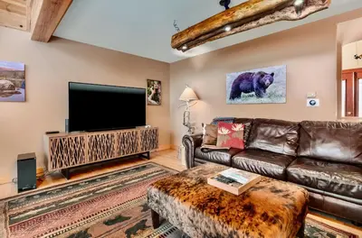 a living room with a leather couch and a flat screen tv at Awestruck Home in Estes Park