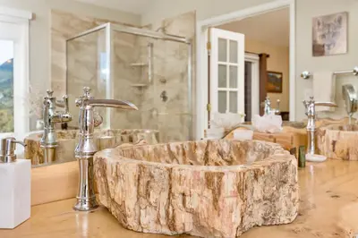 a bathroom with a large wooden tub with a sink at Awestruck Home in Estes Park