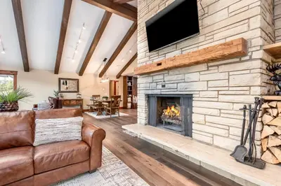 a living room with a stone fireplace with a flat screen tv at Breiding Upper Condominium 2 Bedroom condo in Estes Park