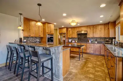a kitchen with wooden cabinets and a island with bar stools at Mapes Home in Estes Park