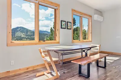 a dining room with a table and chairs and windows at Mapes Home in Estes Park