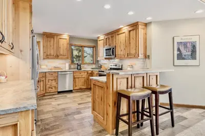 a kitchen with wooden cabinets and a island with bar stools at Dances With Wolves Condominium 3 Bedroom condo in Estes Park