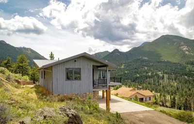 a house on a hill with mountains in the background at Kintzle Home in Estes Park