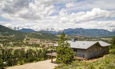 a house on a hill with mountains in the background at Kintzle Home in Estes Park