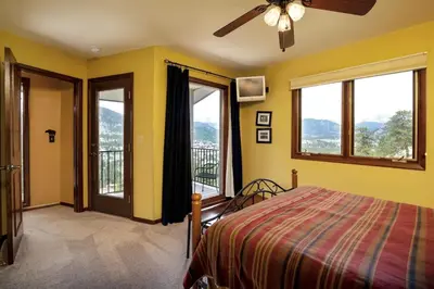 a bedroom with a bed with yellow walls and windows at Kintzle Home in Estes Park