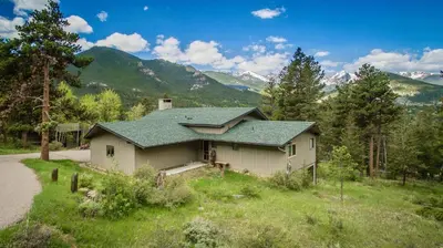 a house in a field with mountains in the background at Salmans Bear Cove Home in Estes Park