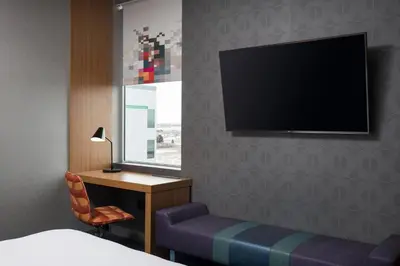 a hotel room with a bed and a desk and a television at Aloft Denver Airport at Gateway Park in Aurora