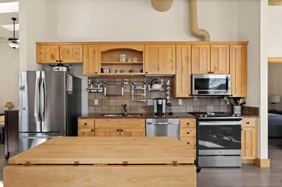 a kitchen with wooden cabinets and stainless steel appliances at Spacious Dtwn Estes Park Loft Condo 4 Mi to RMNP in Estes Park