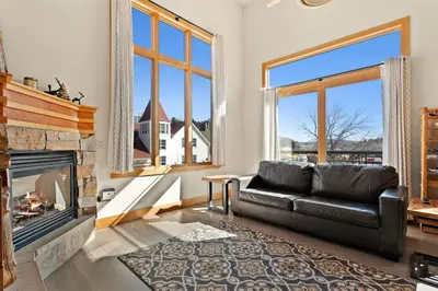 a living room with a leather couch and a fireplace at Spacious Dtwn Estes Park Loft Condo 4 Mi to RMNP in Estes Park