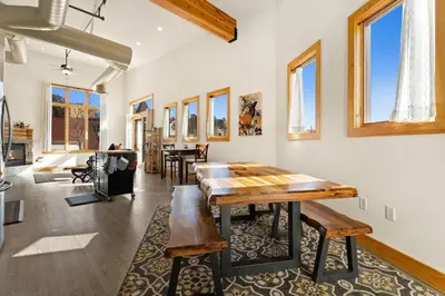 a dining room with a table and some windows at Spacious Dtwn Estes Park Loft Condo 4 Mi to RMNP in Estes Park