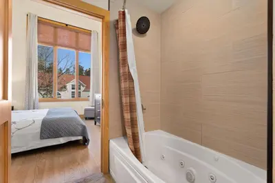 a bedroom with a tub and a bed and a shower at Spacious Dtwn Estes Park Loft Condo 4 Mi to RMNP in Estes Park